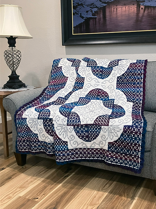 A solid color DK weight acrylic yarn was used for the main (background) color. A gradient and a solid color DK weight yarn were used for the contrasting (design) colors to create the look of the different “quilt” blocks. A size 6/0 (3.50 mm) crochet hook is also needed. Stitch markers are recommended to keep track of your progress. An 18″ square pillow form and 1/2″ round buttons are needed for the pillow.